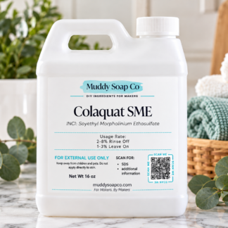 White F-style jug of ColaQuat SME odor-neutralizing ingredient from Muddy Soap Co., featuring the product label, on a marble countertop with towels and greenery.