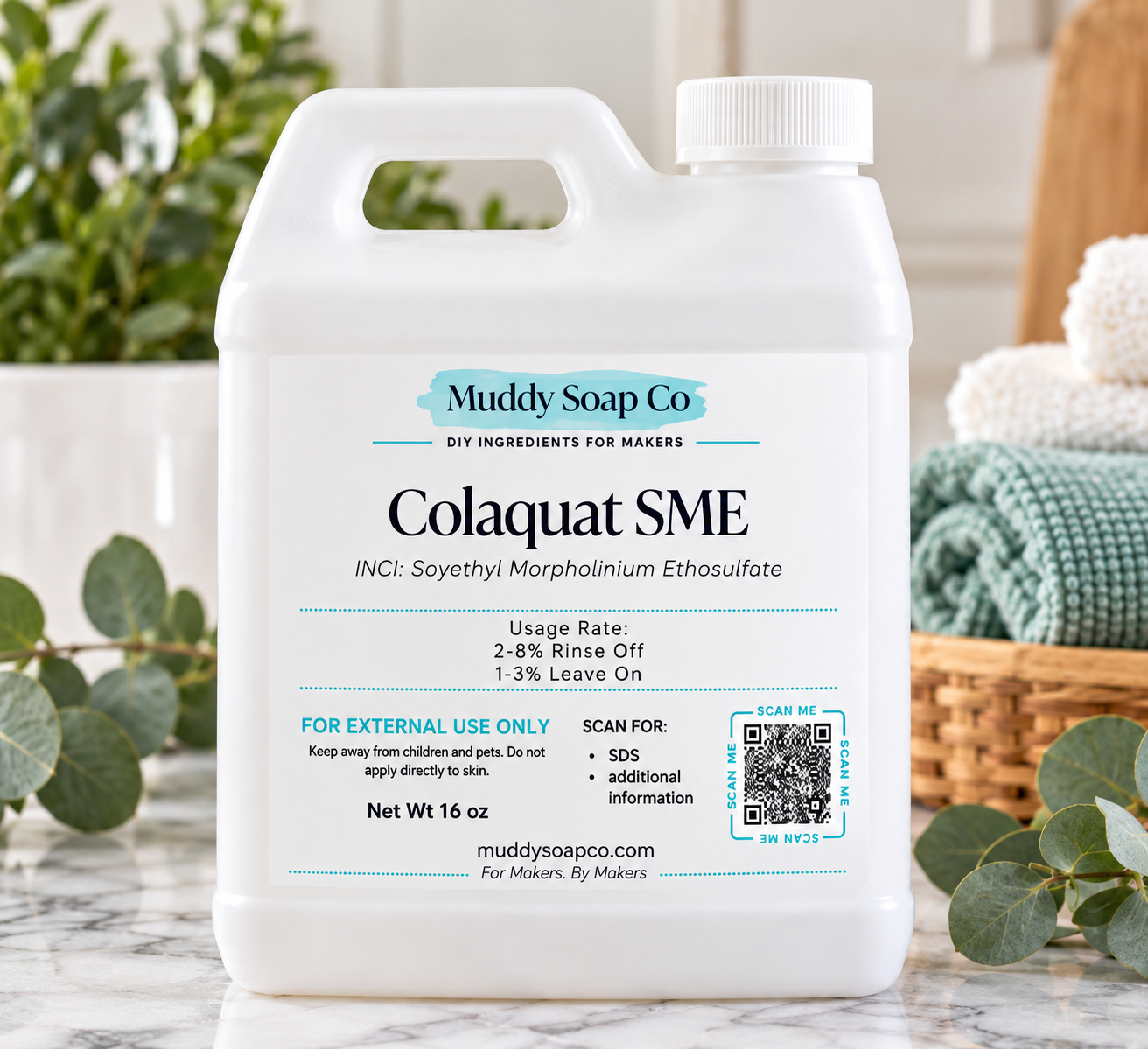 White F-style jug of ColaQuat SME odor-neutralizing ingredient from Muddy Soap Co., featuring the product label, on a marble countertop with towels and greenery.