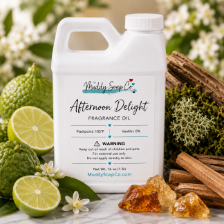 White F-style bottle of Afternoon Delight Fragrance Oil by Muddy Soap Co displayed with fresh limes, bergamot-inspired citrus, moss, teakwood, sandalwood, and warm amber on a white marble surface.
