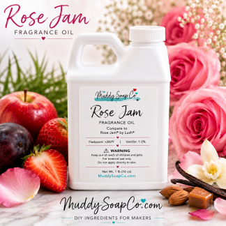 White F-style bottle of Rose Jam Fragrance Oil by Muddy Soap Co displayed with pink roses, strawberries, plums, apples, vanilla beans, and almonds on a marble surface.